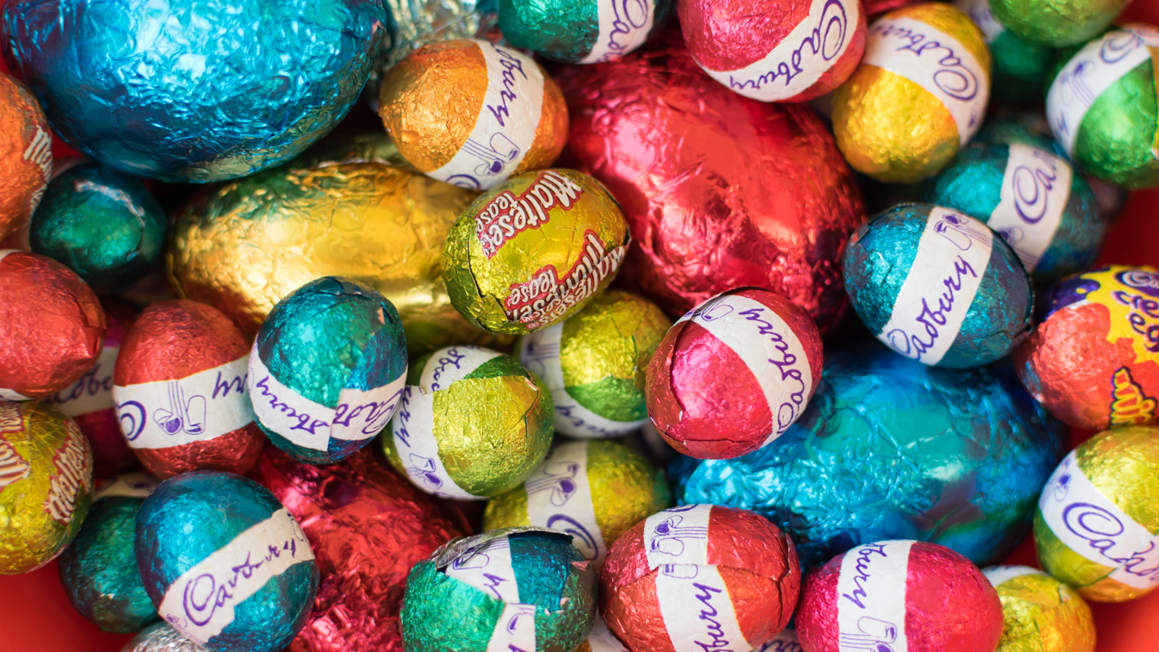 The Bitter Truth About The Sweet Stuff 4 Colorful Foilwrapped Chocolate Easter Eggs With Visible Brand Names.