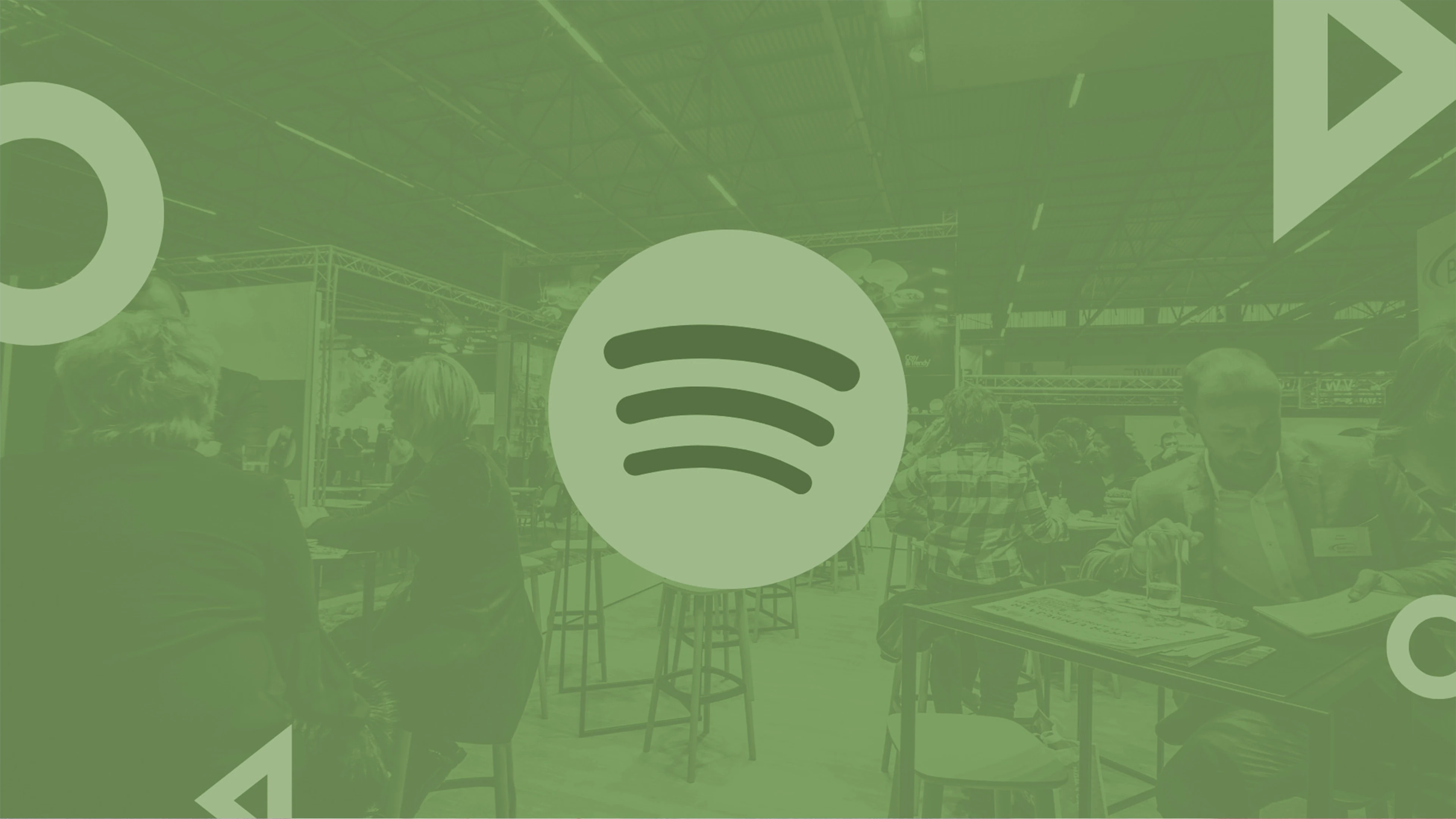 Spotify Logo Over A Gathering In A Spacious Indoor Venue With A Green Tint.