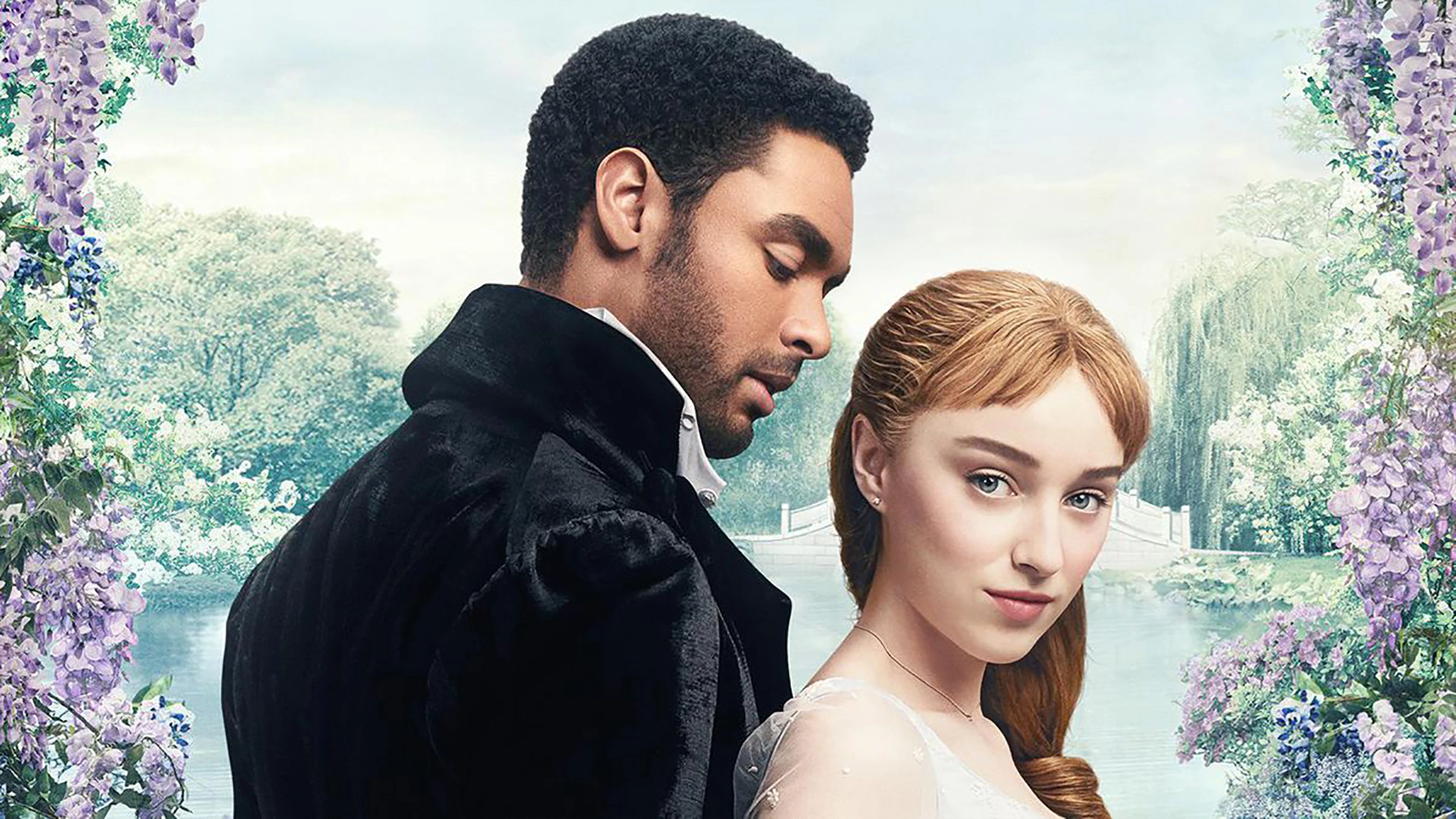 Man And Woman Posing By A River, Framed By Flowers, With Trees And A Bridge In The Background.