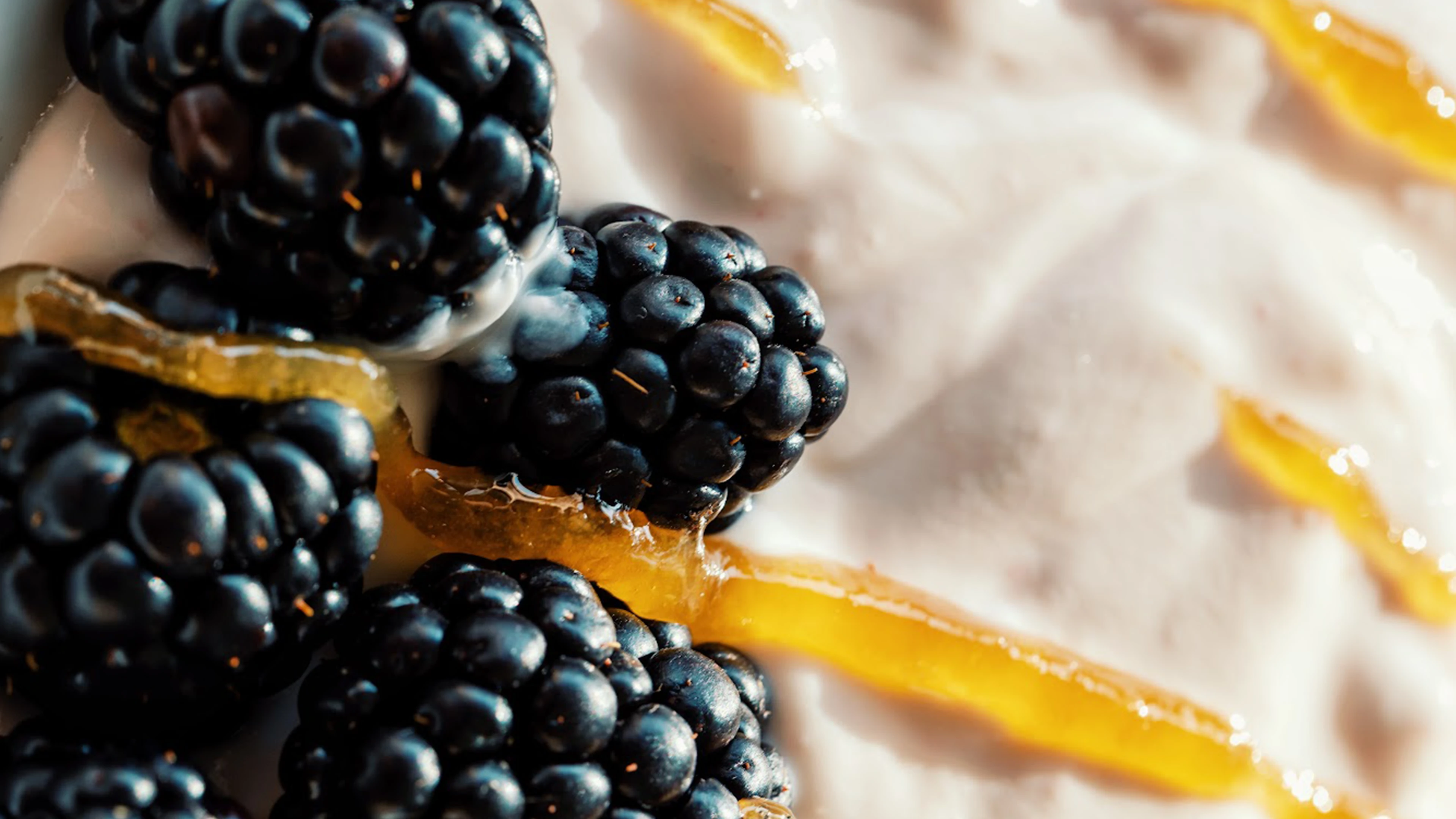 Blackberries on a creamy surface with honey drizzles.