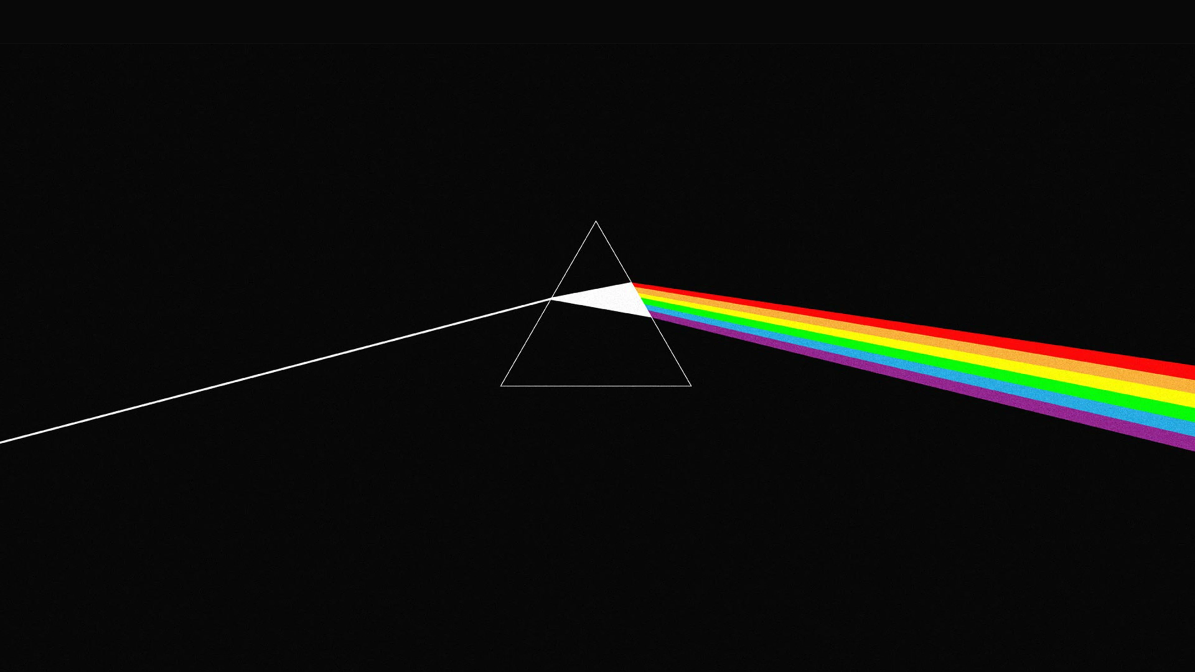 Light beam enters prism, splits into rainbow on black background.