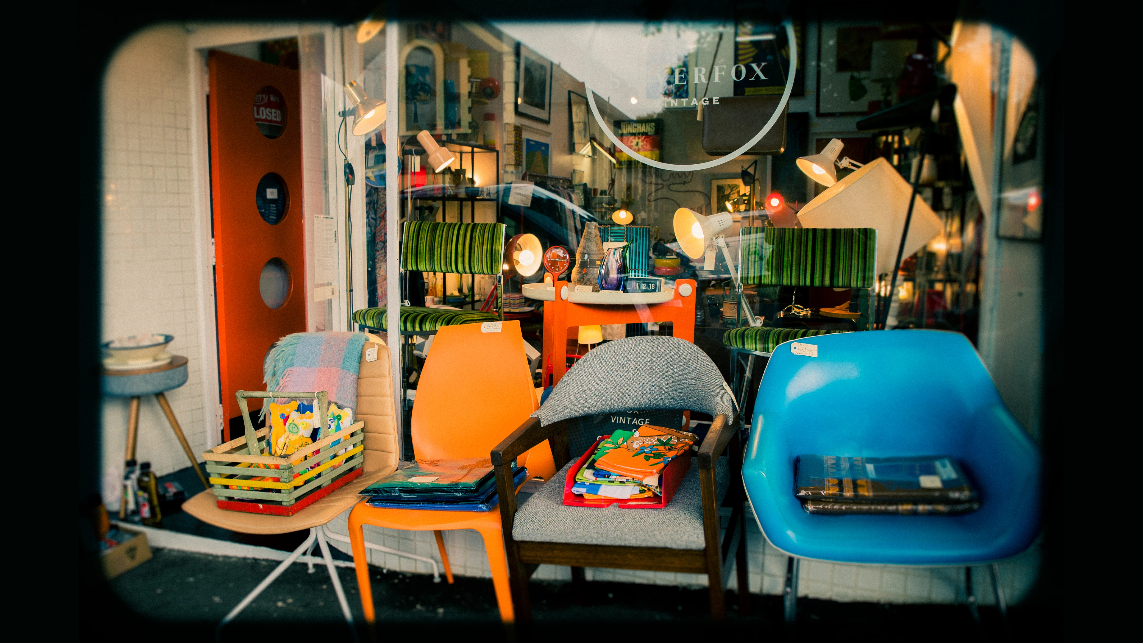 Perks Of Being A Tyneesha: 22 &Amp; Clueless As Ever! 1 Vintage Shop Window With Colorful Chairs, Books, Toys, Greenstriped Decor, And Table Lamps.
