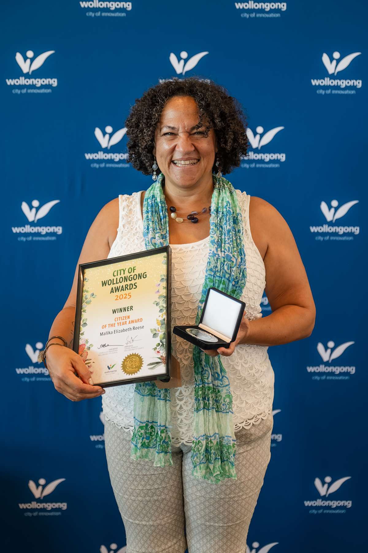 Person with award in front of "Wollongong City of Innovation" backdrop holding certificate and medal.