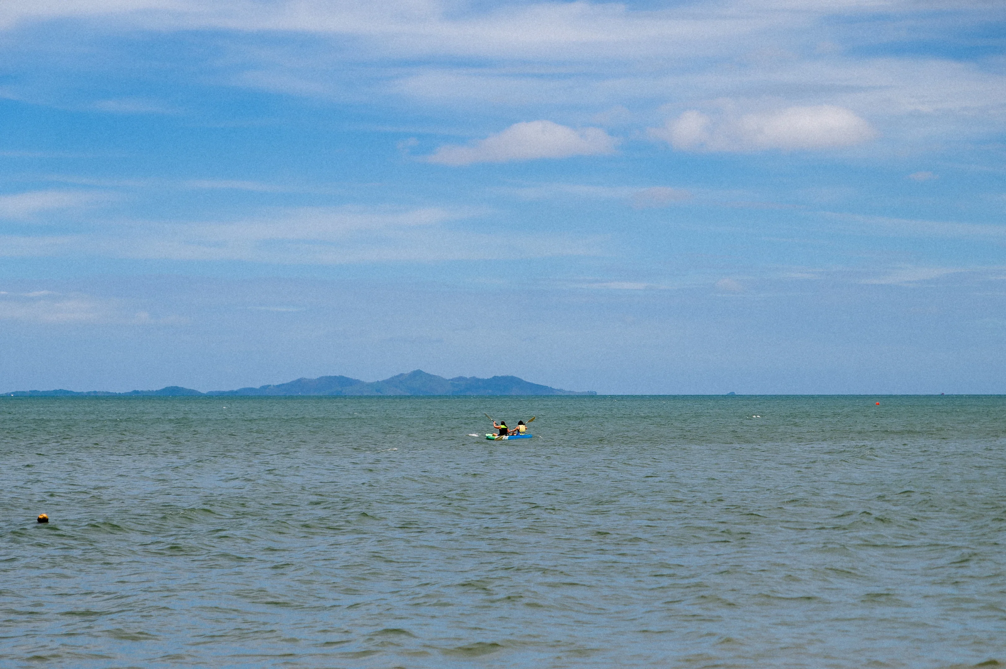 Kayaking On Serene Waters Person Kayaking On A Wide Body Of Water Under Clear Blue Sky With Distant Hills On The Horizon.
