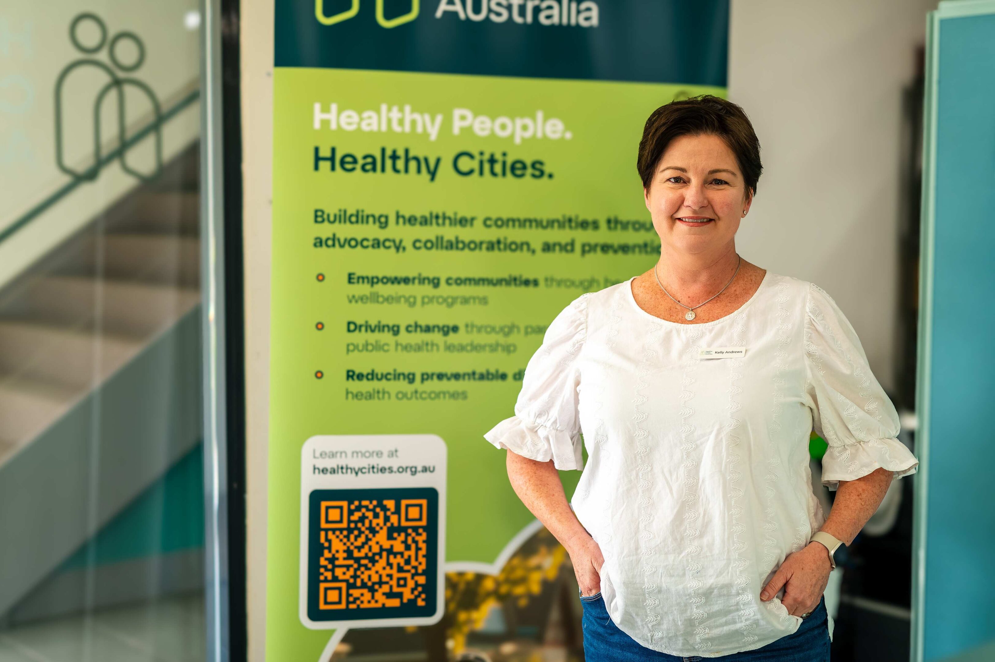 Person Beside Healthy Cities Australia Banner With Qr Code And Website Link.